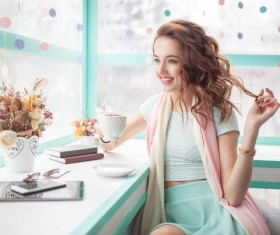 Beautiful young woman holding a coffee playing with hair HD picture