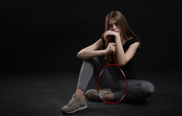 Girl sitting on the floor holding a tennis racket HD picture