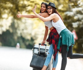 Two women who dragged the suitcase wanted a free ride Stock Photo