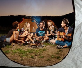 Camping friends sitting next to the campfire Stock Photo