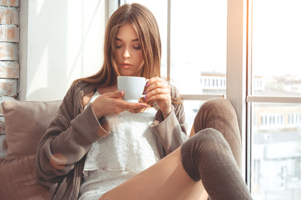 Girl sitting on the windowsill to drink coffee Stock Photo