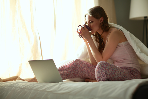 Internet in bed drinking coffee woman Stock Photo