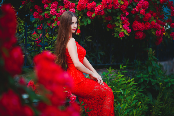 Sitting beautiful girl in red flowers Stock Photo