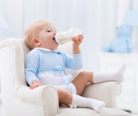 Sitting on a small couch with a baby drinking milk Stock Photo