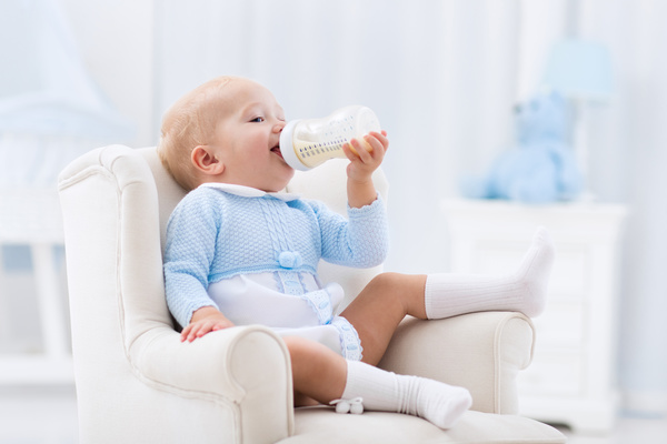Sitting on a small couch with a baby drinking milk Stock Photo