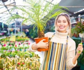 Smiling woman holding potted tropical plants HD picture