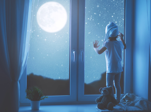 Standing on the windowsill to see the stars of the little girl Stock Photo