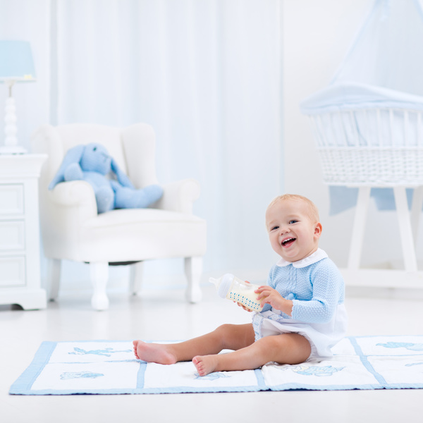 The baby sitting on the carpet is happy to play the bottle Stock Photo