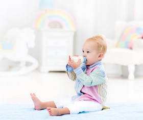 The baby sitting on the floor drinking milk Stock Photo