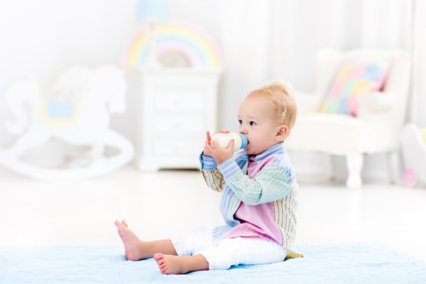 The baby sitting on the floor drinking milk Stock Photo