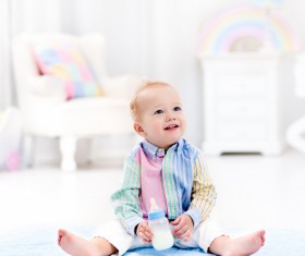 The baby sitting on the floor with the bottle Stock Photo