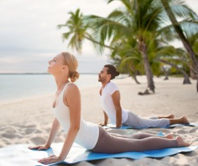 Yoga exercise men and women on the beach Stock Photo