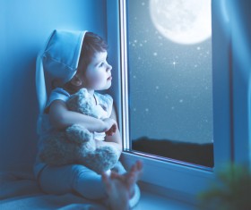 little girl sitting on the windowsill watching the stars Stock Photo