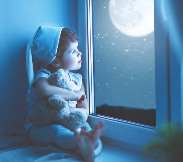 little girl sitting on the windowsill watching the stars Stock Photo