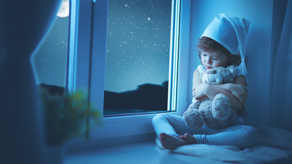little girl sitting on the windowsill with a teddy bear Stock Photo