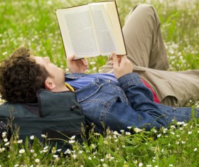 Young man lying on the lawn reading Stock Photo
