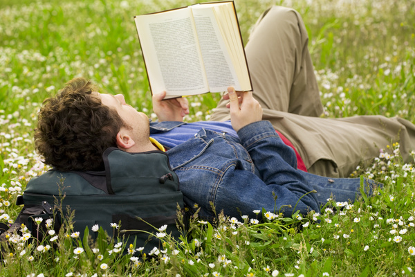 Young man lying on the lawn reading Stock Photo