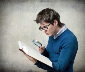 Young man with a magnifying glass to read Stock Photo