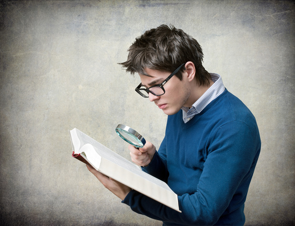 Young man with a magnifying glass to read Stock Photo