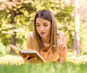 Lying in the grass to read the woman Stock Photo 02