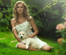 The woman sitting on the grass is holding the dog Stock Photo