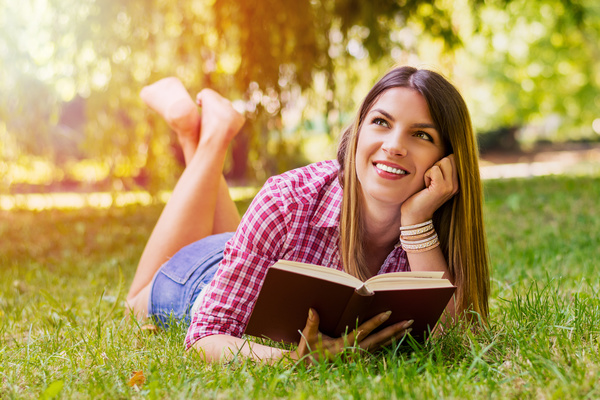 woman holding a book on the grass Stock Photo