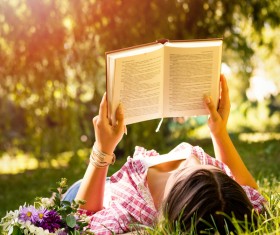 woman lying on the grass reading Stock Photo