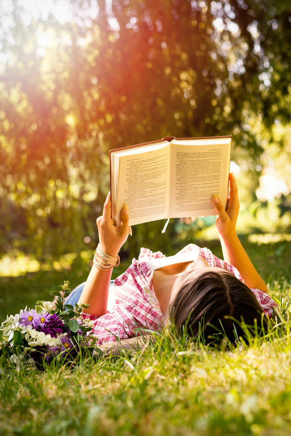 woman lying on the grass reading Stock Photo