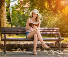 woman sitting on a bench reading a book Stock Photo