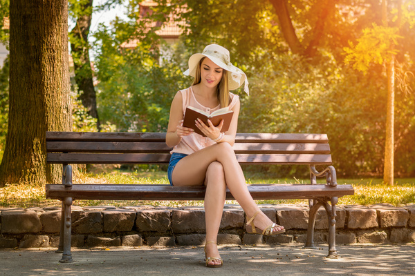 woman sitting on a bench reading a book Stock Photo