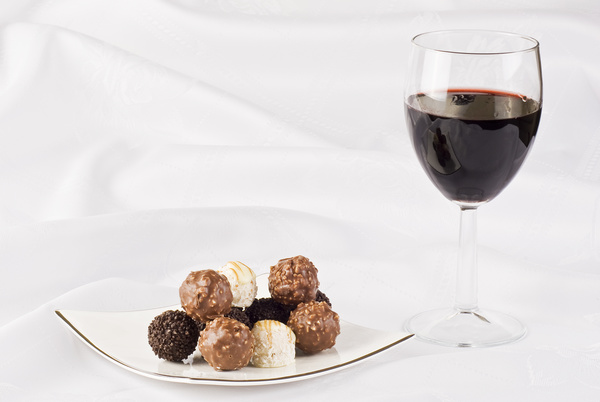 Chocolate candy and red wine on white plate Stock Photo