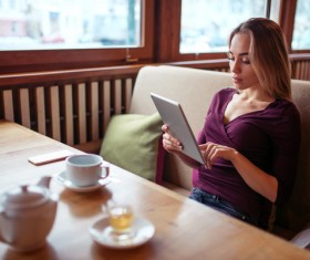 A woman who uses a tablet computer in a coffee shop Stock Photo 01