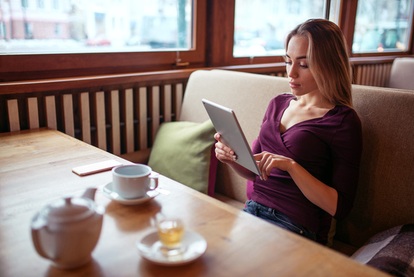 A woman who uses a tablet computer in a coffee shop Stock Photo 01