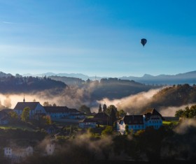 Balloon flying above foggy mountain town Stock Photo