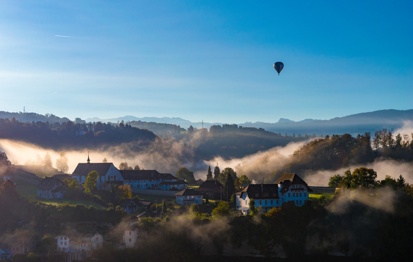 Balloon flying above foggy mountain town Stock Photo