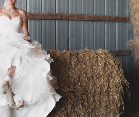 Bride posing with white dress in straw storehouse Stock Photo