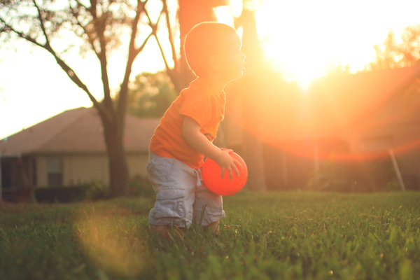 Little boy playing with ball under sunlight Stock Photo