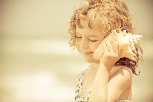 Little girl listening to conch Stock Photo