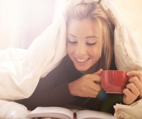 Lying in bed drinking coffee reading girl Stock Photo 01