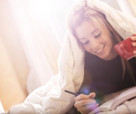 Lying in bed drinking coffee reading girl Stock Photo 02