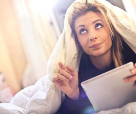 Lying on the bed to see e-book girl Stock Photo