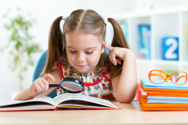Pre-school children who read books with magnifying glass Stock Photo