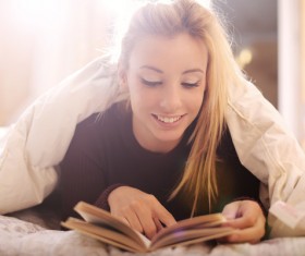 The girl lying on the bed reading Stock Photo 01