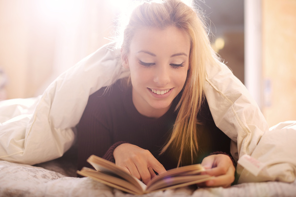 The girl lying on the bed reading Stock Photo 01