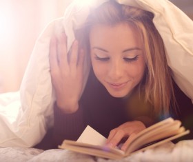 The girl lying on the bed reading Stock Photo 02