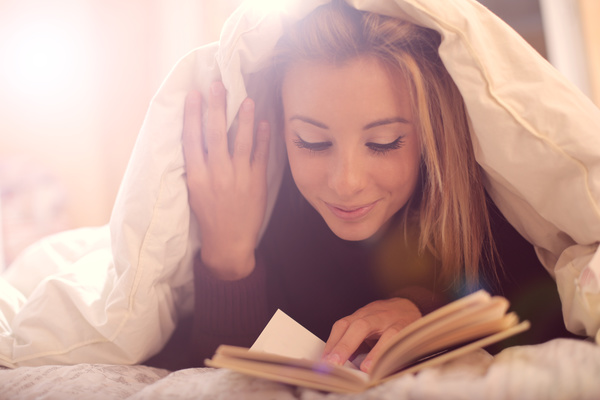 The girl lying on the bed reading Stock Photo 02