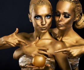 Two women coated with gold powder Stock Photo