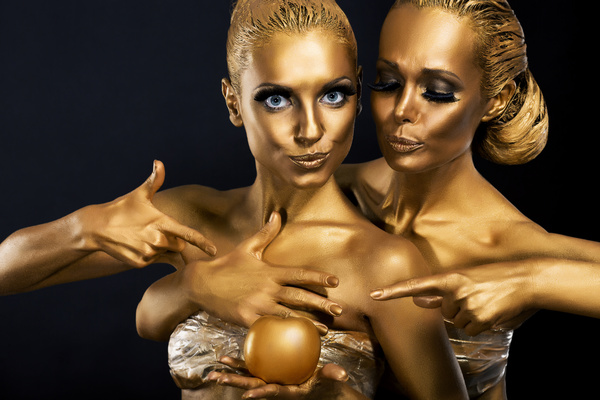 Two women coated with gold powder Stock Photo