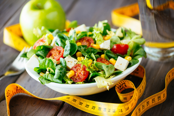 Vegetable salad and tape measure on the table Stock Photo