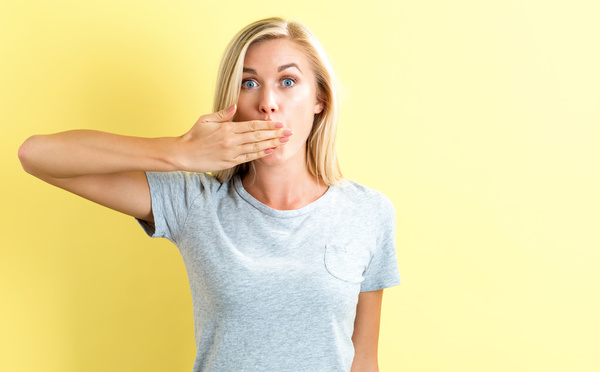 cover ones mouth with hands woman Stock Photo